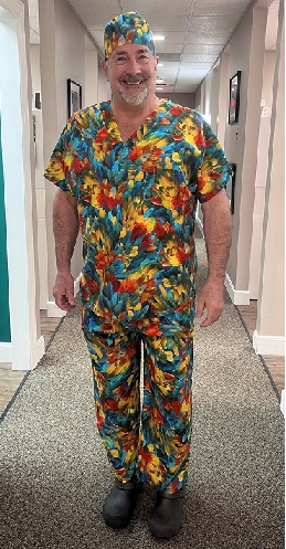 dentish wearing a parrot print scrub top in a hallway