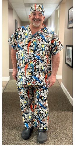 dentish wearing a scrub top of parrots standing in a hallway