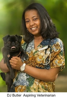 Model wearing a vibrant African animal print scrub top featuring dogs and cats, smiling outdoors while holding a small black dog.